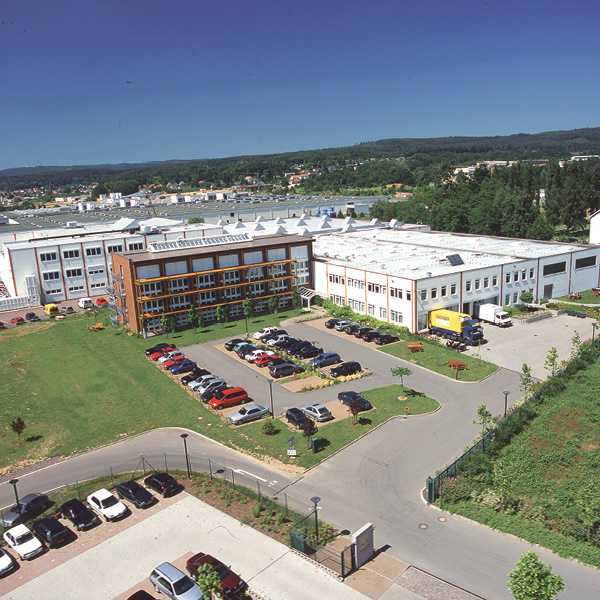 Gebaeude 2001 von oben kohlpharma Gebäude 2001 mit Parkplatz und umgebender Landschaft unter klarem Himmel.
