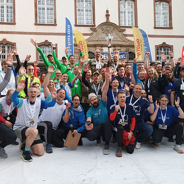 City Biathlon Merzig Siegerfeier City Biathlon Merzig Menschen jubeln mit Medaillen und Trophäen vor historischem Gebäude.