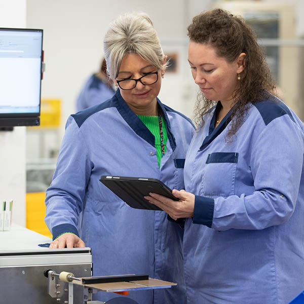 Zwei Mitarbeiterinnen in kohlpharma Produktionsumgebung arbeiten zusammen an einer Maschine.