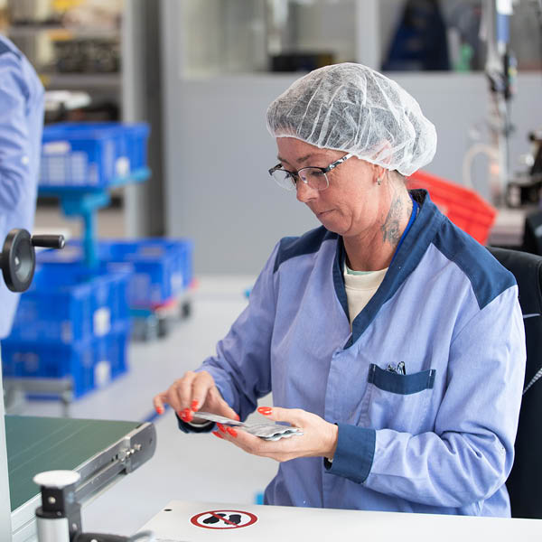 Arbeiterin-Import-Produktion Eine Mitarbeiterin in Produktionskleidung arbeitet konzentriert